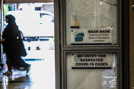 A woman walks behind a restaurant door pasted with an old covid-19 warning written 'no entry for suspected covid-19 cases' at a Mall in Nakuru. Kenya's covid-19 transmission rate has remained low even as China cases surged necessitating lockdowns.