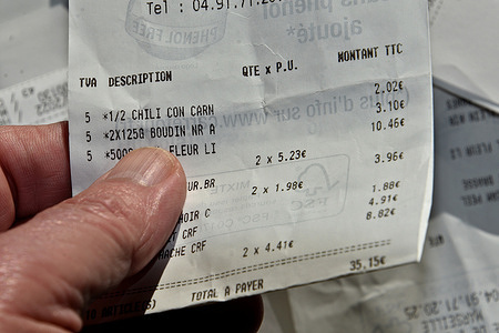 A man holds a purchase receipt between his fingers. In application of law n°2020-105 of February 10, 2020 relating to the fight against waste and the circular economy, receipts will no longer be automatically printed by the merchant from January 1, 2023. To obtain a printed receipt, the consumer will now have to expressly request it from the merchant.