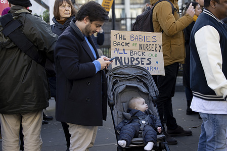 A supporter seen with his young child and placard to support the nurses on strike outside St Thomas’ Hospital. Healthcare professionals from St Thomas’ Hospital join the rally in solidarity with the nurses at the Royal College of Nursing Union who staged the second day of national strikes in dispute of salary rise and working conditions in the NHS with the UK government.