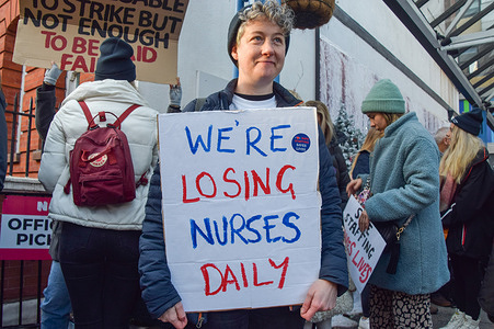 A nurse holds a placard which states 'We are losing nurses daily' during the demonstration at the picket line outside Great Ormond Street Hospital. Nurses and Royal College of Nursing members have walked out for the second day of the first UK nurse strike in NHS history. Thousands of nurses across the country are on strike in a dispute over pay.