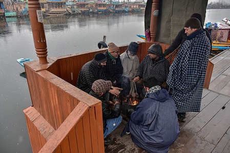 Residents gather around the bonfire as they warm themselves during snowfall. Parts of Kashmir valley including Srinagar received snowfall leading to the closure of the vital Srinagar-Jammu national highway and cancellation of flight operations, officials here said.