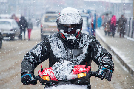 A motorcyclist rides through a street during a heavy snowfall on the outskirts of Srinagar. Most parts of Kashmir received fresh snowfall that leading to the closure of Kashmir capital's main highway that connects disputed region with the rest of India.