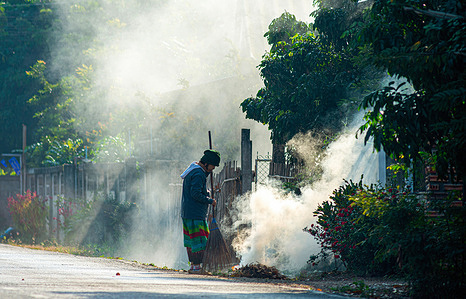 A person is seen amid a cloud of smoke from burning leaves in front of a house in Lamphun. Air pollution is a problem that generally affects northern Thailand. The pollution leads to an increase in health issues among the local population.
