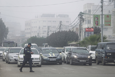 A Palestinian security man walks on the street during a foggy morning.