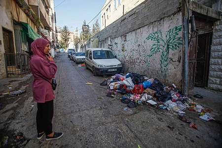 A woman is looking at the garbage piles up in the streets of Balata camp during the UNRWA strike. The United Nations Relief and Works Agency for Palestine Refugees (UNRWA) made a general strike in the Balata camp, east of Nablus, in the West Bank. All UNRWA institutions closed to refugees in the West Bank in protest of the agency management's decision to reduce social services and the endowment of Jamal Abd God, the head of the Workers Union in the West Bank.