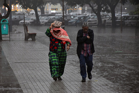 Residents walk along the street as it rains in Chandigarh.