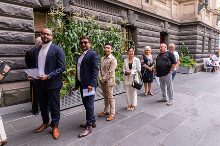 A diverse group of citizens-to-be gather outside Melbourne Town Hall on Australia Day, eagerly awaiting the start of their citizenship ceremony.