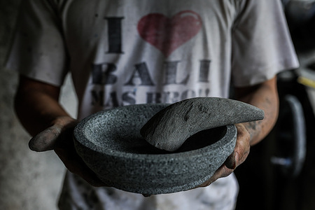 An artisan shows off a traditional mortar and pestle at a workshop in Bogor. Local artisans can make 5-6 mortars and pestles in one working day. Each item costs between IDR 10,000 to IDR 30,000 (approx 50 cents to two dollars). The traditional mortar and pestle is distributed around Indonesia and has penetrated Asian markets such as Malaysia, Thailand, and Vietnam.