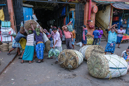 Vegetable vendors are busy transporting the vegetables in a market.