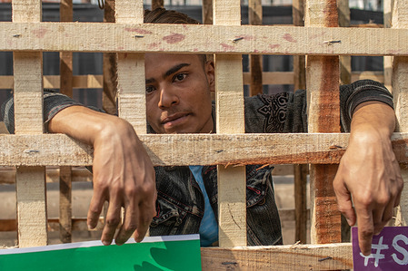 A protester seen sitting inside a wooden cage during the demonstration. Anti-zoo campaigners staged a protest near the National Museum in Dhaka, demanding the shutdown of zoos.