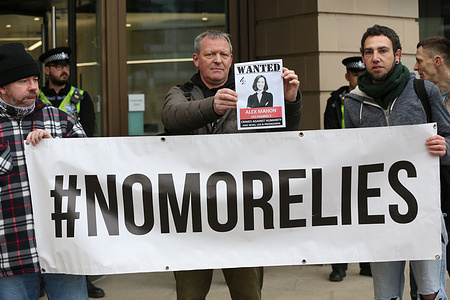 A protester holds a placard with a photo of Channel 4 CEO saying ‘Wanted Alex Mahon - for crimes against Humanity’, behind a ‘No More Lies banner as police prevent protesters from approaching the Channel 4 building. Freedom campaigners march across the city centre and demonstrate outside media companies. The ‘Media is the Virus’ event is taking place in cities across the UK and internationally. The protesters feel the media organizations have told lies throughout the Covid-19 restrictions, refusing to allow the protesters side of the argument to be heard. They also feel they are ignoring the yellow card scheme and the covid-19 vaccine injured, are inaccurate reporting climate change and increasingly support the setting up of smart cities.