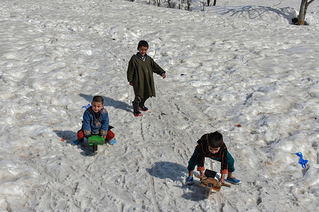Kashmiri children play in a snow covered field during a sunny winter day in Tangmarg, about 50kms from Srinagar, the summer capital of Jammu and Kashmir.