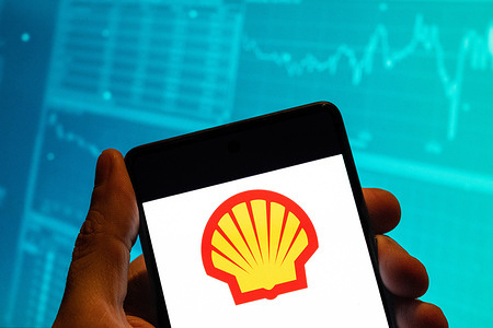 In this photo illustration, the Anglo-Dutch global group of energy and petrochemical company Shell logo is seen displayed on a smartphone with an economic stock exchange index graph in the background.