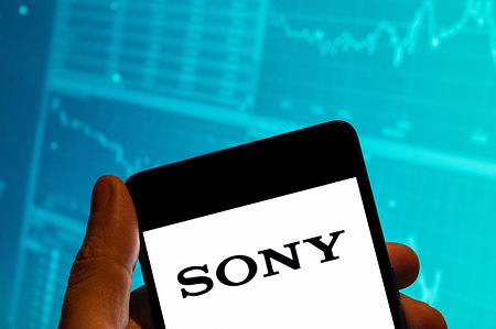 In this photo illustration, the Japanese multinational technology conglomerate corporation Sony logo is displayed on a smartphone screen with an economic stock exchange index graph in the background.