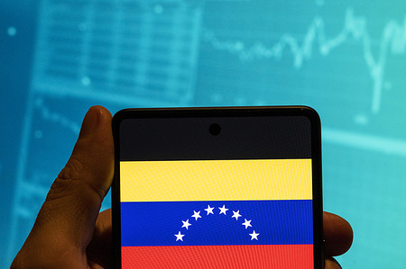 In this photo illustration, the Bolivarian Republic of Venezuela flag is seen displayed on a smartphone with an economic stock exchange index graph in the background.