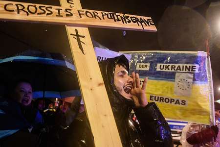 A protester shouts slogans as he holds a cross with the inscription that says "this cross is for Putin grave" during an anti-war rally to mark the first anniversary of Russia's full-scale invasion of Ukraine.