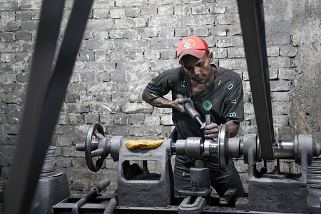 A teenage boy is seen working at a aluminum factory in Dhaka. Aluminum Factory is very common in Bangladesh where different kinds of pot and jar are made from aluminum. Such industry creates a sound source of employment. Among these workers many of them are children aged less than 15 years.