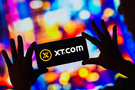 In this photo illustration, the XT.com logo seen displayed on a smartphone.