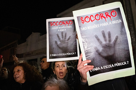 A teacher is seen amongst placards saying "socorro" (help) during the demonstration. Teachers demonstrated for their right to fight for better conditions in their teaching career as they have now been summoned to minimum services because of the years of service that were frozen and lost during the economic crisis years.