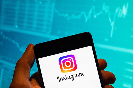 In this photo illustration, the American photo and video-sharing social networking service owned by Meta Platforms, the Instagram logo is seen displayed on a smartphone with an economic stock exchange index graph in the background.
