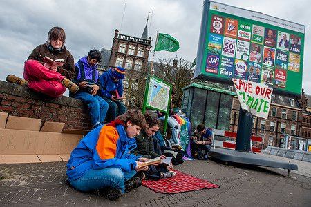 Protesters seen reading books about the climate during the demonstration. A group of young people and students gathered in the center of The Hague, to carry out a read-in action, to keep demanding better climate policy and to stop the destruction of the lands of MAPA (Most Affected Peoples and Areas). The action consists in sitting on the floor and pretend to be reading a book about the climate, under one of the billboards, announcing the next Dutch municipal elections. The climate young organization #FridaysForFuture created by Greta Thunberg organized this action in the Dutch city.