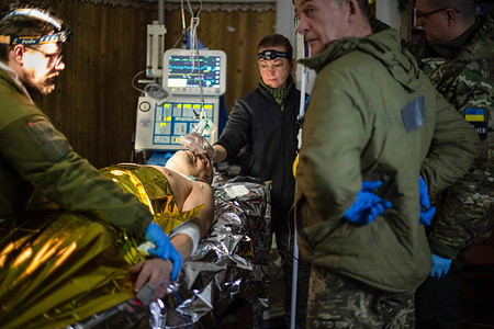 A military medical team treats a Ukrainian soldier who was shot in the chest at the Bakhmut front by a Russian sniper, at a stabilization center in an undisclosed location.