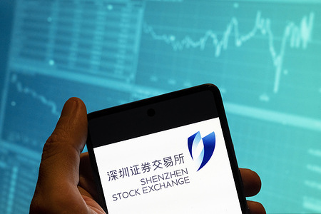 In this photo illustration, the Shenzhen Stock Exchange (SZSE) logo is seen displayed on a smartphone with an economic stock exchange index graph in the background.