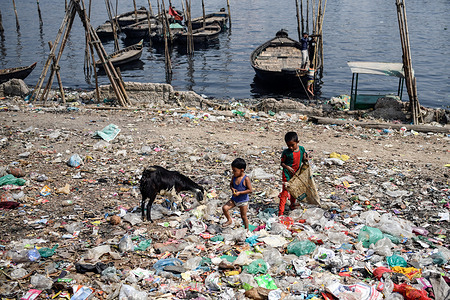 Children playing on a hill of plastic waste on the bank of the polluted river Buriganga in Dhaka. The pollution of the Buriganga river has been serious for years now due to the liquid waste discharged from the textile industries. The waste discharge caused the water of the Buringaga river turns pitch-black.