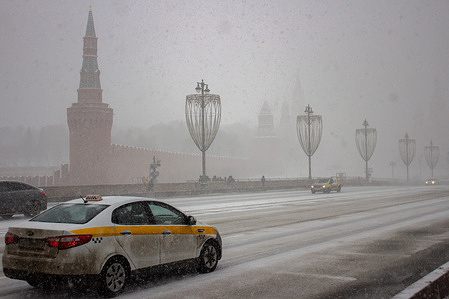 Cars pass on the Bolshoi Moskvoretsky Bridge with The Kremlin seen in the background during a snowstorm that hit Moscow.