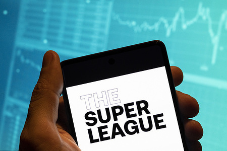 In this photo illustration, the Super League, commonly referred to as the European Super League (ESL) competition logo is seen displayed on a smartphone with an economic stock exchange index graph in the background.