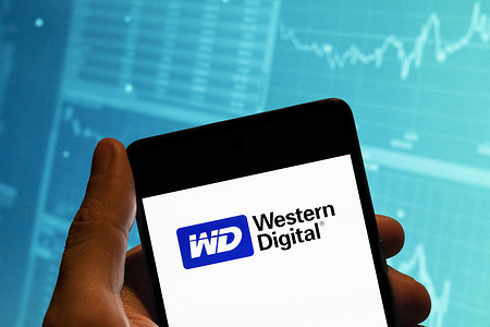 In this photo illustration, the American computer hard disk drive and data storage manufacturer Western Digital (WD) logo is seen displayed on a smartphone with an economic stock exchange index graph in the background.