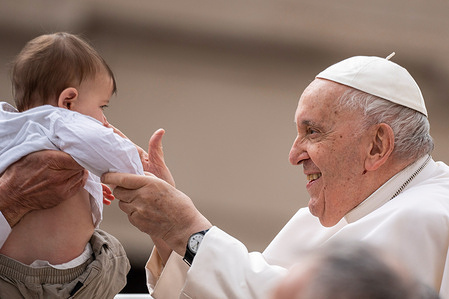 Pope Francis greets and blesses a child during his traditional Wednesday General Audience at St. Peter's Square in Vatican City.