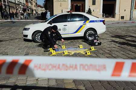 A man dressed as a police officer, a police car, and a Ukrainian map seen during a street action 'Who will punish the criminal?' in Lviv. The non-government organization (NGO), "In the heart with Ukraine", organized the protest in Lviv. During the protest, activists set up a crime scene with an actor dressed as a police officer and aUkrainian map laid out as a victim. The protest was designed to draw the world's attention to Russia's crimes in Ukraine.
