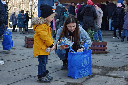 A woman and child go through a WFP (World Food Programme) bag as people receive food at a humanitarian aid distribution point in Zaporizhzhia. Since the onset of the Russian invasion, nearly one-third of Ukrainians have been forced from their homes. This is one of the largest human displacement crises in the world today, according to the UN Refugee Agency. People in areas directly affected by conflict are in immediate need of life-saving support including food.