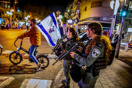 An Israeli man rides a bicycle with the Israeli flag next to armed border police women at a crossroad after a shooting terror attack on Dizingof street. Palestinian militant group Hamas claimed responsibility for the Tel Aviv terror shooting attack on Thursday night that wounded three Israelis. The attack in the heart of the city came after a day of protesting by Israeli opposition against Netanyahu’s government.