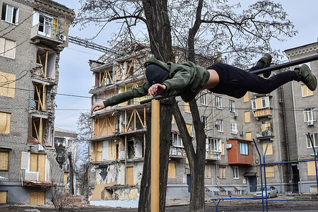 A teenager seen practicing on the horizontal bar near the apartment building damaged by a Russian shelling. The children and families of Ukraine have endured a year of escalating violence, trauma, destruction, and displacement. Children continue to be killed, wounded and deeply traumatized by the violence that has sparked displacement on a scale and speed not seen since World War II.