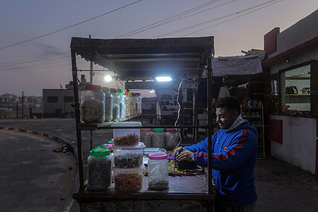 A Palestinian man works at a kiosk on the seashore in the northern Gaza Strip during sunset.