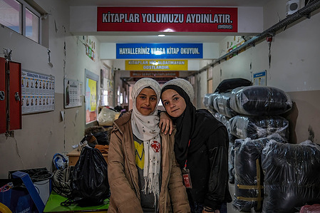 Meryem and Muna pose in front of a sign reading "Books Light Up Our Way" written by Ovid inside Sümer Secondary School in Dulkadiroğlu district. Meryem and Muna (earthquake victims) visit their school that was damaged in Kahramanmaraş, Turkey.