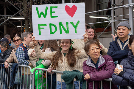 A spectator holds a placard reading "WE LOVE FDNY" during the St. Patrick's Day Parade along 5th Avenue in New York City.