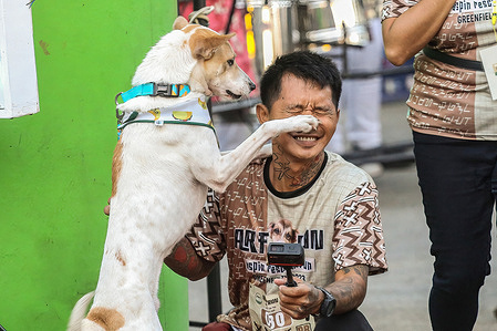A man plays with his dog before the start of a fun run.