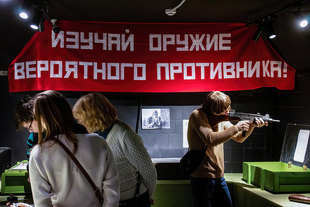 A teenager examines Uzi, a machine pistol developed in Israel, at the Guns Dungeon interactive museum in Moscow. The text on the poster above saying "Study the weapons of a potential enemy!"