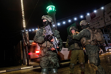 Israeli soldiers stand guard near the site of a shooting attack on a Jewish settler's car in the town of Hawara, south of Nablus, in the West Bank. A Palestinian carried out a shooting attack on a settler's car while it was in the middle of the market in the town of Hawara.