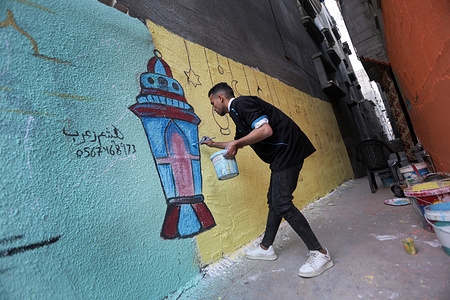 A Palestinian paints a mural for the month of Ramadan in the streets of Khan Yunis, in the southern Gaza Strip, as part of the preparations for the holy month of Ramadan.