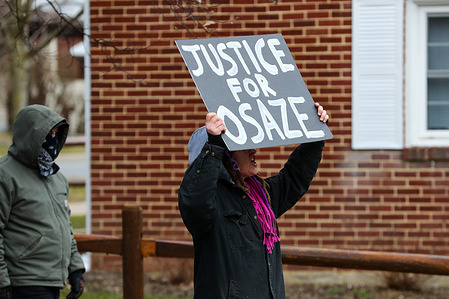 A woman holds a placard as she marches with protesters to the site where State College police killed Osaze Osagie. The 3/20 Coalition organized a protest to mourn and demand justice for Osaze Osagie, a Black man who was shot and killed by State College police in 2019. According to the local media, Osagie was experiencing a mental health crisis when police went to his apartment to involuntarily transport him to the hospital. The police said he was wielding a knife.