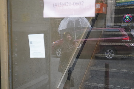 A lady shelters under an umbrella while walking on the street during rainfall. There were couple of storms that came to San Francisco Bay Area last three months and caused floods, snowing, road closure, downed trees, power outages and other impacts. The weather in San Francisco Bay Area has not been stable since December last year and has rained many times. The residents here want the sunny days back.