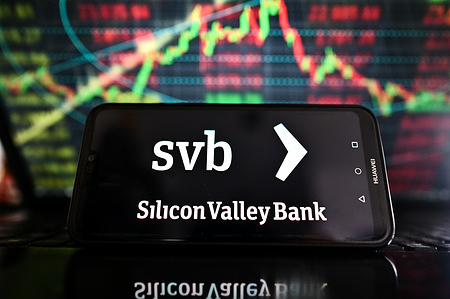 In this photo illustration, a Silicon Valley Bank logo is displayed on a smartphone with stock market percentages on the background.