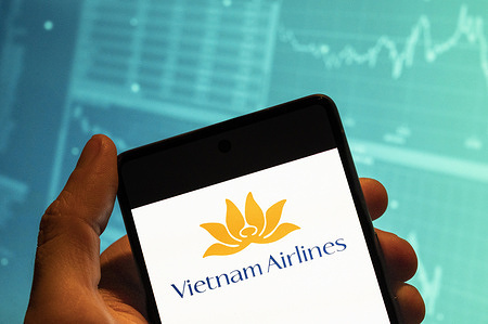 In this photo illustration, the Vietnamese airline Vietnam Airlines logo seen displayed on a smartphone with an economic stock exchange index graph in the background.