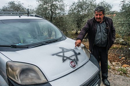 A Palestinian man inspects a car with the Star of David graffiti spray painted by the Jewish settlers at night in the city of Salfit in the occupied West Bank. In the night Jewish settlers sprayed the spray and wrote slogans in the city of Salfit.