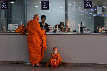 Monk and novice monk seen buying a train ticket at Bang Sue grand station in Bangkok.