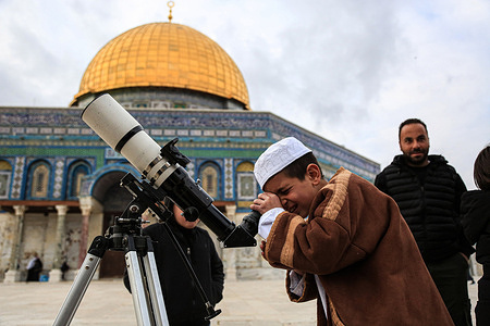 A child uses a telescope to search for the moon to mark the start of Islam's holy month of Ramadan near the Dome of the Rock shrine at the Aqsa mosque compound in the old city of Jerusalem. A group of Palestinians gathers at Al-Aqsa Mosque to observe the new crescent Moon, which is believed to appear on the first day of Ramadan, in Jerusalem.